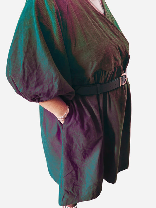 Person wearing a red dress with puffed sleeves on a wooden deck.