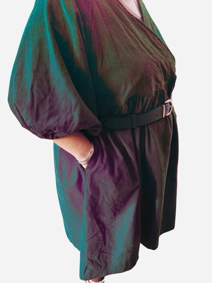 Person wearing a red dress with puffed sleeves on a wooden deck.