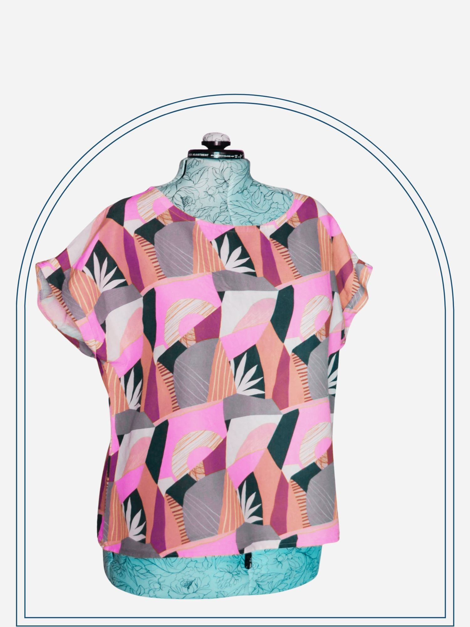 A mannequin displaying a colorful geometric patterned shift blouse, tunic, or dress with sleeves and a round neckline.