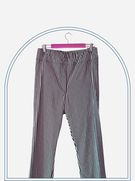 A pair of striped stretch jeans hanging on a wooden hanger against a white wall.