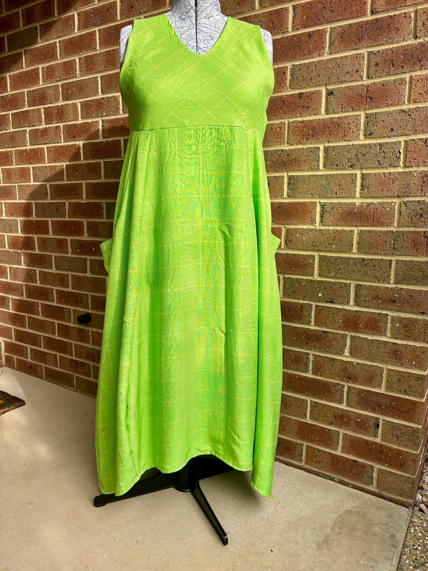 Green dress on a mannequin against a brick wall.