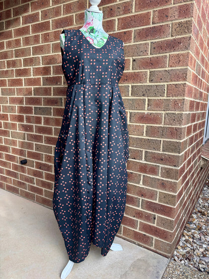 Black dress with red spots pattern on a mannequin against a brick wall.