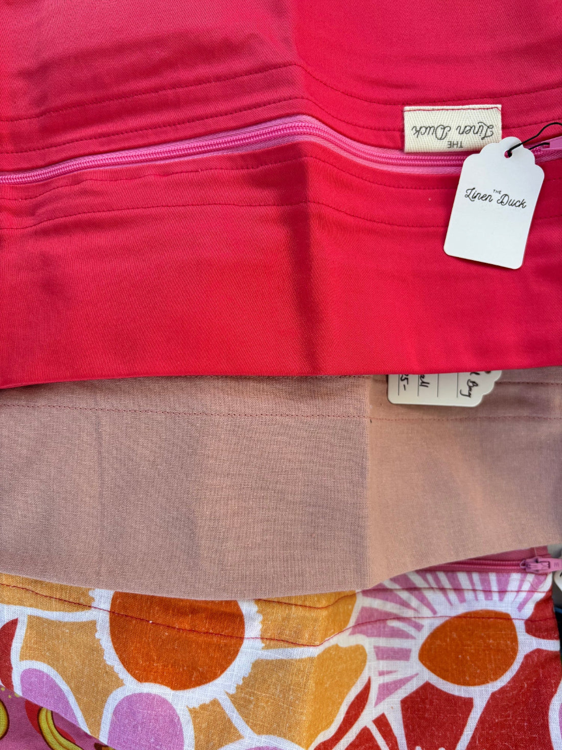 Close-up of a red fabric with a tag and another piece of fabric with a colorful pattern.